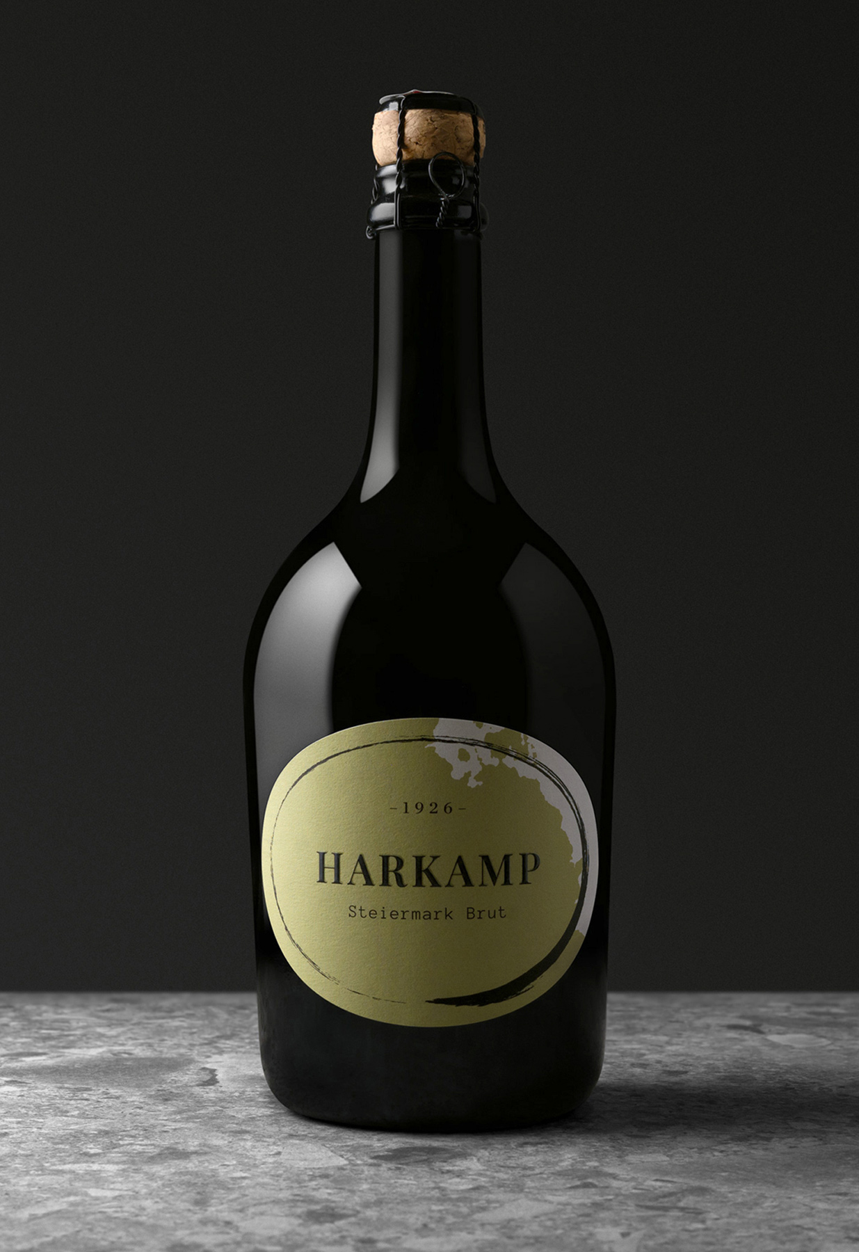 Schwarze Sektflasche mit Etikett „HARKAMP Steiermark Brut“ vor dunklem Hintergrund.